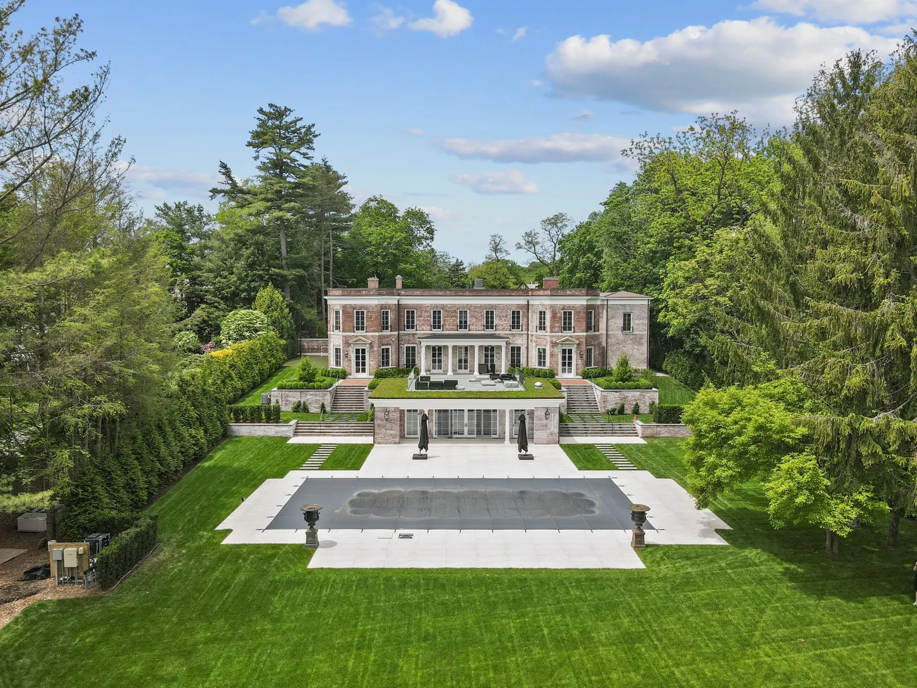 A classical brick estate with terraced lawns and a stone pool terrace